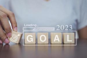 Loading new year 2023 with goal wooden blocks on table. Start the new year 2023 with a business goal plan. photo