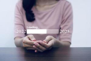 mujer de negocios sosteniendo una barra de descarga virtual con un medidor de progreso de carga que cambia el año 2022 a 2023. foto