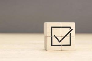 Corporate regulatory and compliance. Goals achievement and business success. Task completion. Wooden cube with checkmark icon. Copy space photo
