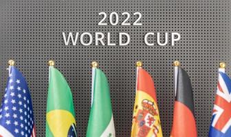 2022 World Cup text on a board and group of different flags of participating countries photo