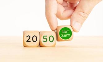 2050 year Net Zero carbon neutral concept. Hand picking a Net Zero symbol Wooden blocks with text. Copy space photo