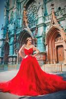 Beautiful woman in long red dress and in royal crown nearly catholic cathedral photo