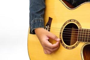Focus on the hands of the child or teenager playing acoustic guitar on white background. Learning and relax concept. photo