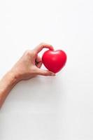 mano de mujer con corazón rojo sobre fondo blanco. concepto de cuidado, salud, seguro y día del amor. foto