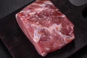 Fresh piece of raw pork with spices, salt and herbs on a wooden cutting board photo