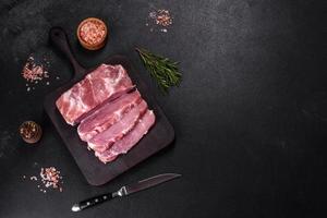 Fresh piece of raw pork with spices, salt and herbs on a wooden cutting board photo