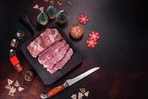 Fresh piece of raw pork with spices, salt and herbs on a wooden cutting board photo