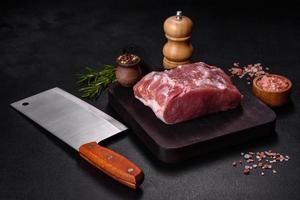 Fresh piece of raw pork with spices, salt and herbs on a wooden cutting board