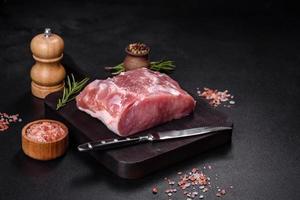 Fresh piece of raw pork with spices, salt and herbs on a wooden cutting board photo