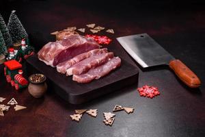 Fresh piece of raw pork with spices, salt and herbs on a wooden cutting board photo