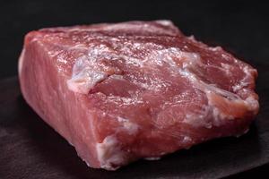 Fresh piece of raw pork with spices, salt and herbs on a wooden cutting board photo