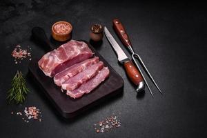 Fresh piece of raw pork with spices, salt and herbs on a wooden cutting board photo