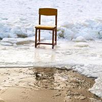 silla icebound en el borde del agujero de hielo en el lago congelado foto