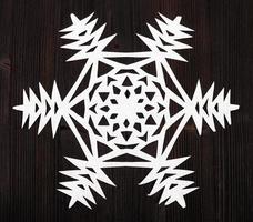 snowflake cut out of paper on dark brown surface photo