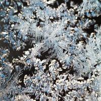 snowflakes and frost pattern on glass close up photo