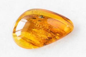 tumbled Amber gem stone on white marble photo