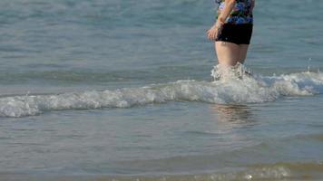 mujer caminando descalza sobre las olas de la playa nai harn, phuket video