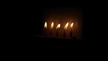 velas no escuro. cinco velas de cera acesas. detalhes do rito religioso. chama é amarela. queima calma. video