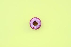 Single small plastic donut lies on a pastel colorful background. Flat lay minimal composition. Top view. photo
