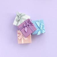 Pile of a small colored gift boxes with ribbons lies on a violet background. Minimalism flat lay top view photo