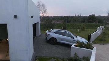 voiture de luxe garée dans la villa privée moderne en dehors de la ville. vidéo aérienne de la maison privée avec l'aston martin dbx707 de luxe garée à côté. video