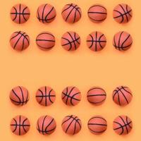 Many small orange balls for basketball sport game lies on texture background of fashion pastel orange color paper in minimal concept photo