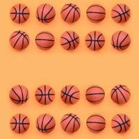 muchas pelotas naranjas pequeñas para el juego deportivo de baloncesto se encuentran en el fondo de textura del papel de color naranja pastel de moda en un concepto mínimo foto