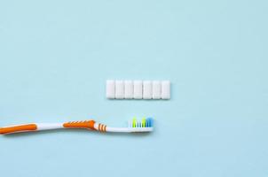 Toothbrush and chewing gums lie on a pastel blue background. Top view, flat lay. Minimal concept photo