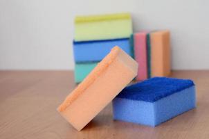 A few kitchen sponges lie on a wooden kitchen countertop. Colorful objects for washing dishes and cleaning in the house are ready for use photo