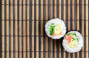 Sushi rolls lies on a bamboo straw serwing mat. Traditional Asian food. Top view. Flat lay minimalism shot with copy space photo