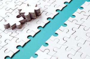 The blue path is laid on the platform of a white folded jigsaw puzzle. The missing elements of the puzzle are stacked nearby. Texture image with space for text photo
