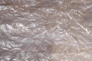 Texture of white crumpled cellophane surface transparent on sunlight. Concept of materials for packaging, product protection against damage photo