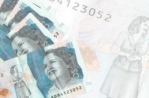 2 Colombian pesos bills lies in stack on background of big semi-transparent banknote. Abstract business background photo