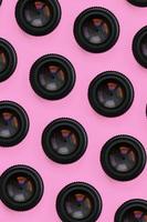 A few camera lenses with a closed aperture lie on texture background of fashion pastel pink color paper in minimal concept. Abstract trendy pattern photo