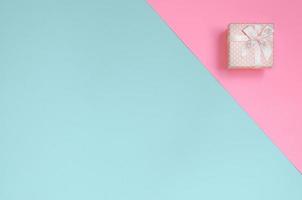 Small pink gift box lie on texture background of fashion pastel blue and pink colors paper in minimal concept photo