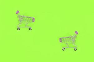 Shopping addiction, shopping lover or shopaholic concept. Small empty shopping cart lies on a pastel colored paper background. Flat lay minimal composition, top view photo