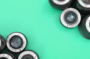 Several photographic lenses lie on a bright turquoise background. Copy space photo