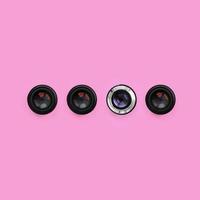 A few camera lenses with a closed aperture lie on texture background of fashion pastel pink color paper in minimal concept. Abstract trendy pattern photo