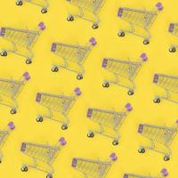 Shopping addiction, shopping lover or shopaholic concept. Many small empty shopping carts perform a pattern on a pastel colored paper background. Flat lay composition, top view photo