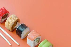 Different types of asian sushi rolls on orange background. Minimalism top view flat lay with Japanese food photo