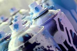 A lot of dirty and used aerosol cans of bright blue paint. Macro photograph with shallow depth of field. Selective focus on the spray nozzle photo