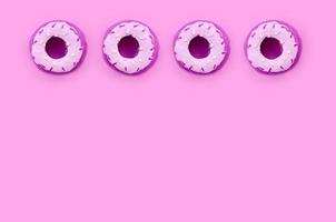 Many small plastic donuts lies on a pastel colorful background. Flat lay minimal pattern. Top view photo