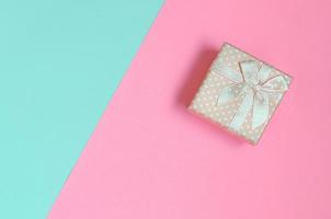 Small pink gift box lie on texture background of fashion pastel blue and pink colors paper in minimal concept photo