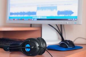 Big black headphones lie on the wooden desktop of the sound designer photo