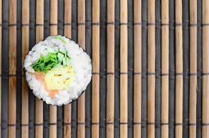 Sushi roll lie on a bamboo straw serwing mat. Traditional Asian food. Top view. Flat lay minimalism shot with copy space photo