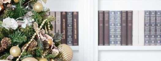 A beautiful decorated Christmas tree on the background of a bookshelf with many books of different colors. Christmas background image of the library photo