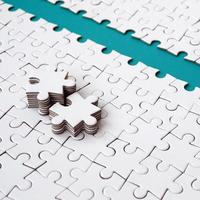 The blue path is laid on the platform of a white folded jigsaw puzzle. The missing elements of the puzzle are stacked nearby. Texture image with space for text photo