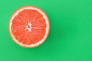 Top view of an one grapefruit slice on bright background in green color. A saturated citrus texture image