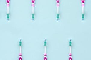 A lot of toothbrushes lie on a pastel blue background. Top view, flat lay. Minimal concept photo