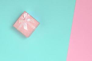 una pequeña caja de regalo rosa se encuentra en el fondo de textura de papel de colores azul pastel y rosa de moda en un concepto mínimo foto